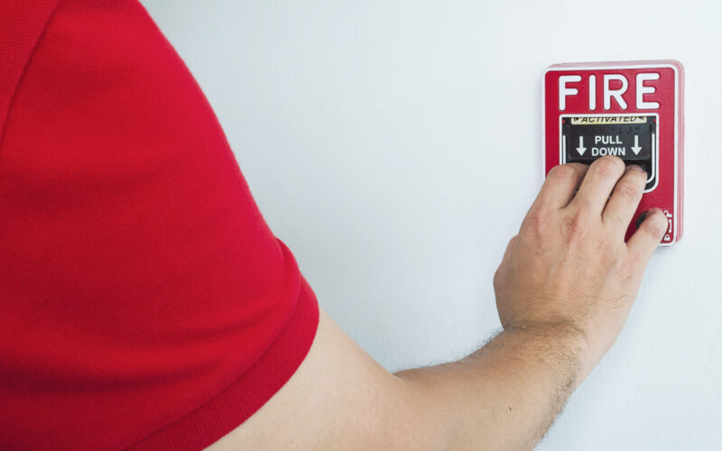 Man is reaching his hand to push fire alarm hand station